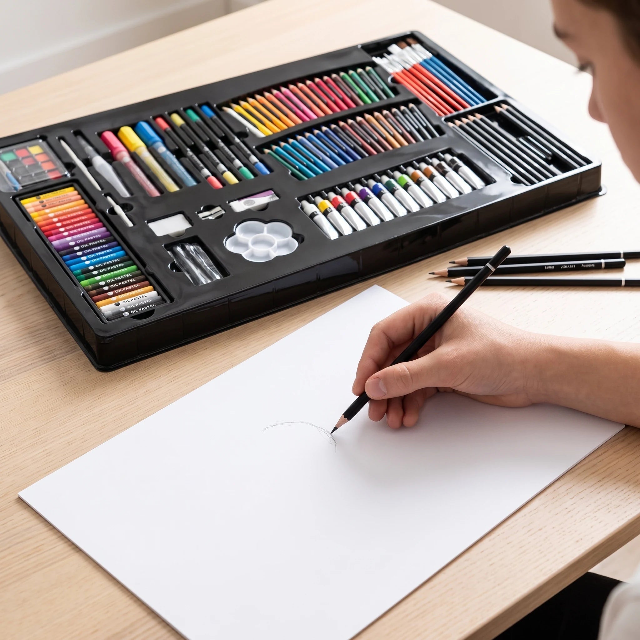 Sketching with a graphite pencil beside the art set tray